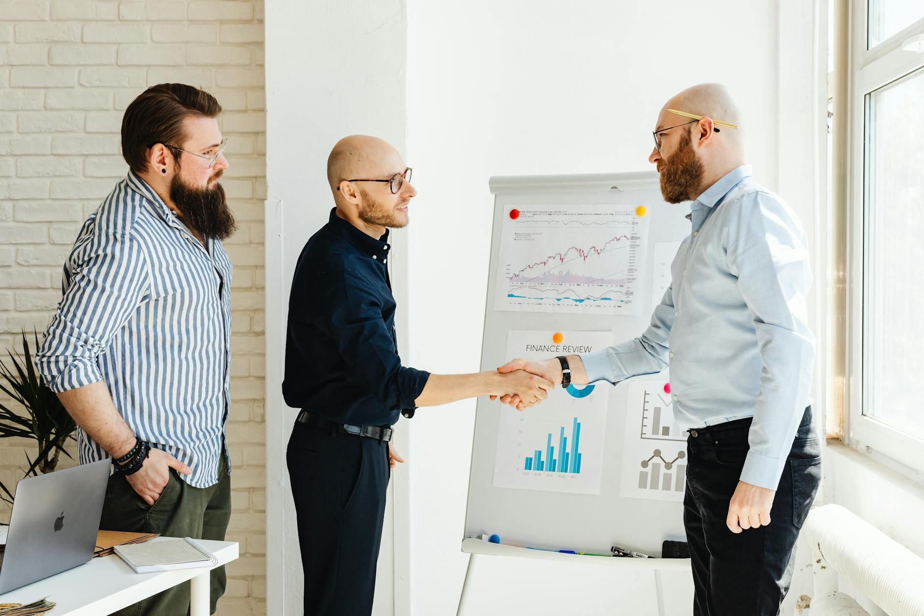 Two people shaking hands across a business meeting table, illustrating the counterparty trust signals that matter in B2B wholesale deals.