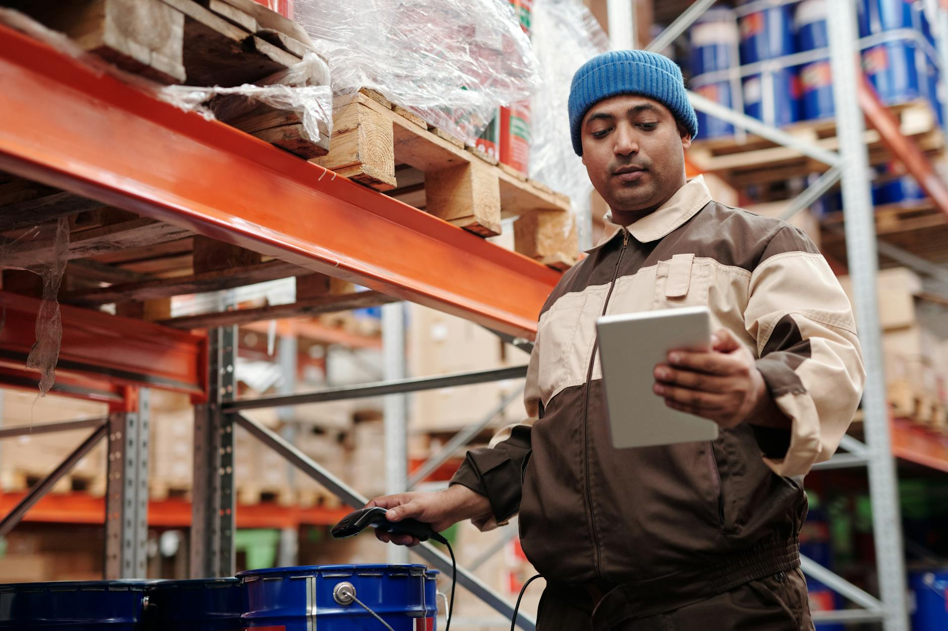 Logistics worker scanning a box label at a warehouse, illustrating inbound shipment verification.